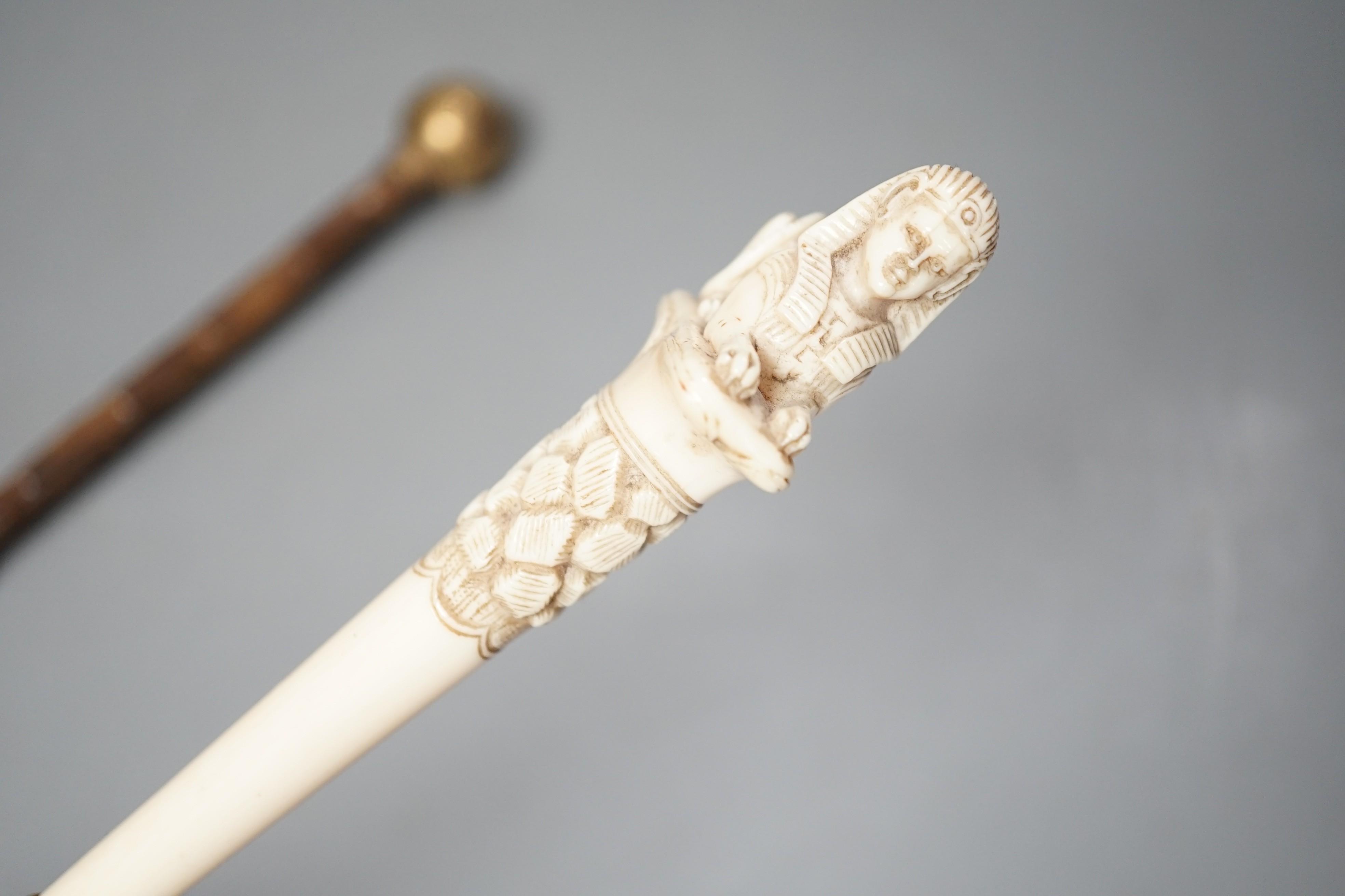 An early 20th century ivory ‘sphinx’ parasol handle, 84cm, together with another gold and iron damascened parasol handle, 62cm